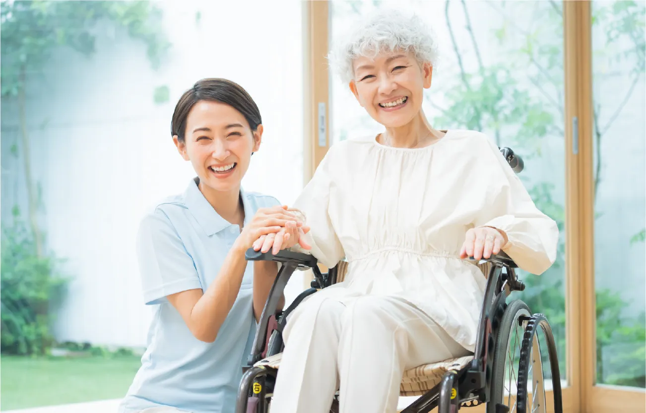 車椅子の高齢者と介護人の写真